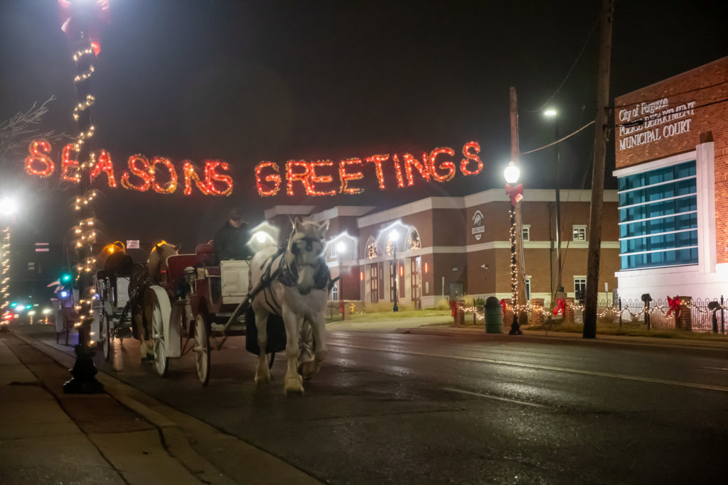 A horse and carriage pass under the Season's Greetings lighted banner in a scene from a past year's festivities.